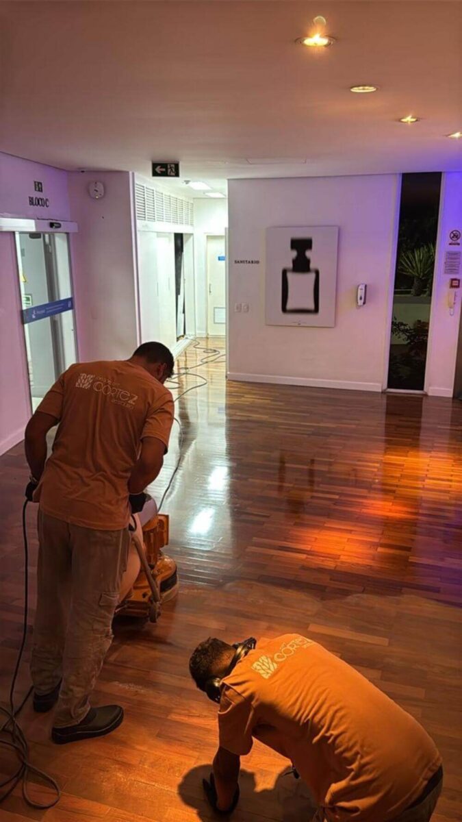 dois colaboradores da Cortez Restaura utilizando maquinário para restaurar o piso de madeira na IFF